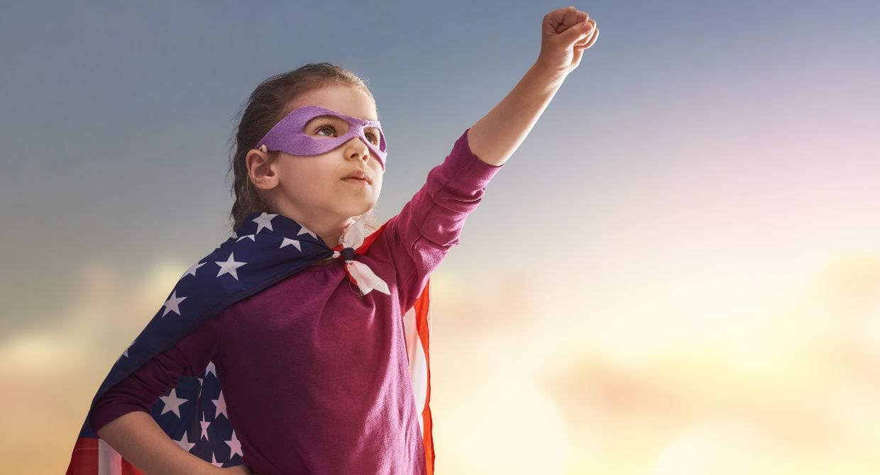 Girl wearing an American flag like a super hero